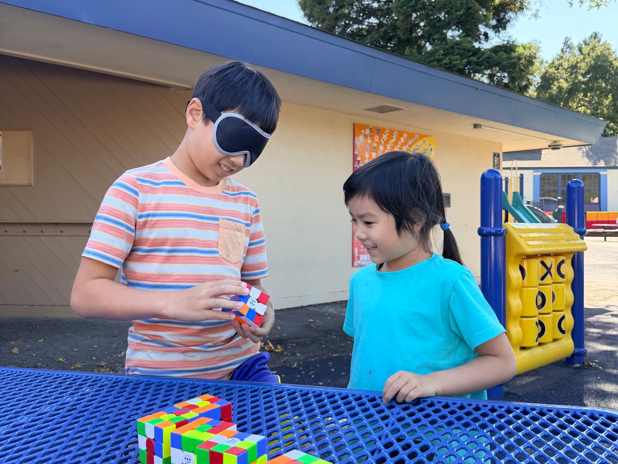 Two students cubing together, one wearing a blindfold